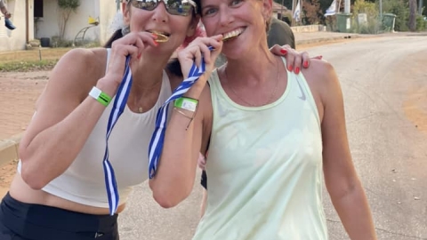 שתיים ממשתתפות מרוץ צופית נוגסות במדליית הזכייה במרוץ בחיוך.jpg